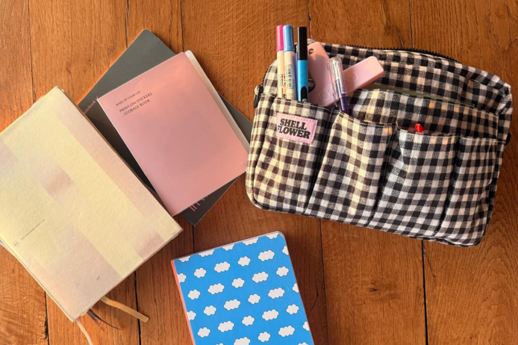 Carnets, planner et trousse à crayons posés sur une table en bois