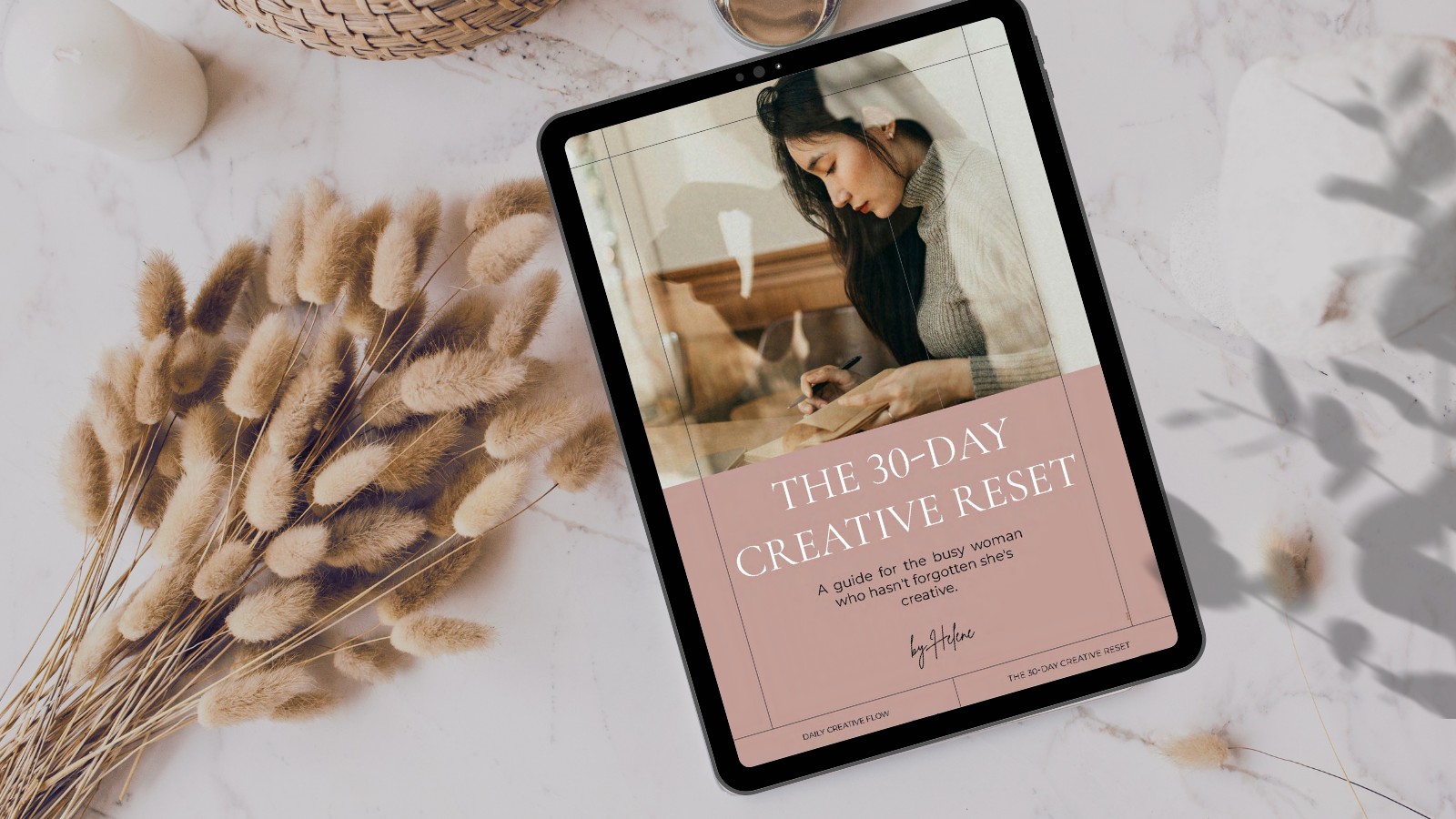 The 30-Day Creative Reset guide open on a tablet, resting on a marble table with dried flowers